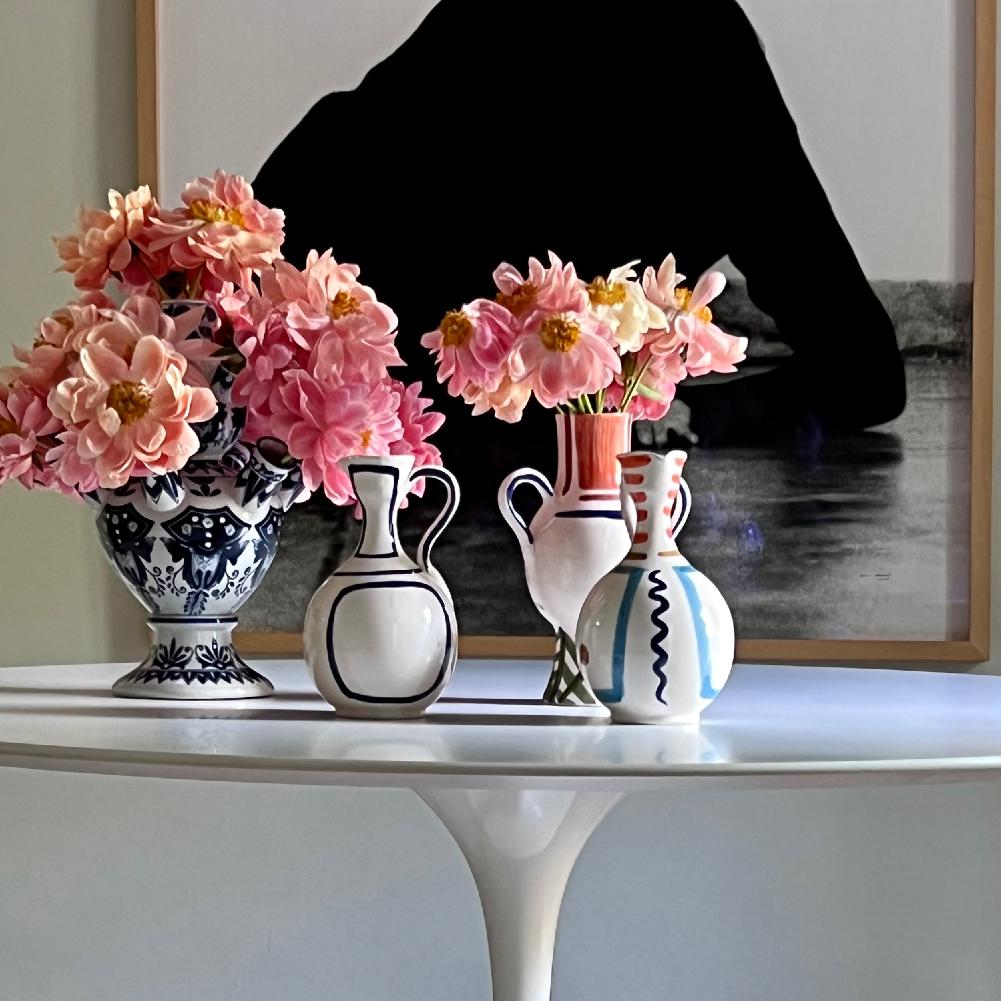 Mesa decorada con jarrones con flores y un cuadro al fondo
